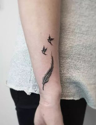 Tatouage plume de petite taille, sur l'avant bras avec deux oiseaux